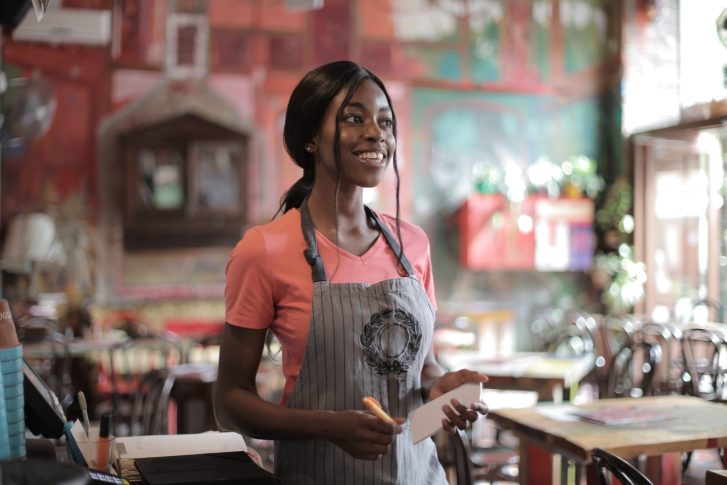 Woman wearing apron while holding white paper