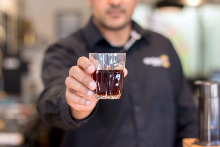 Selective focus photo of man s hand holding drinking glass with liquid inside